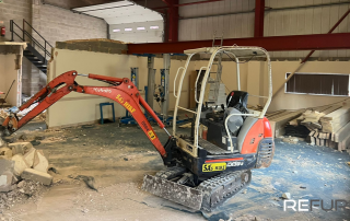 A small digger inside a warehouse during a commercial renovation project run by Refurb