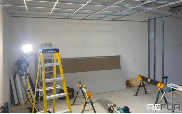 A warehouse interior, undergoing refurbishment, showing step ladders and other equipment.